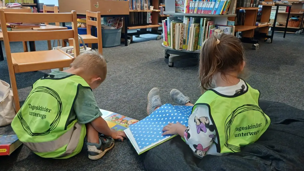 Kinder sitzen in der Bücherei auf dem Boden und lesen Bücher. (c) KibeV
