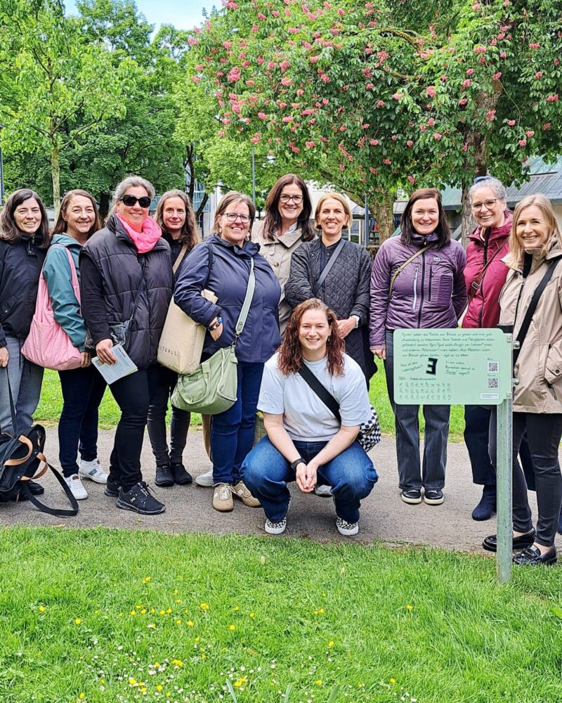 Gruppenfoto unserer Regionalleitungen im grünen Kulturhauspark vor unserem Kinderrechte-Schild "Recht auf Bildung". (c) KibeV