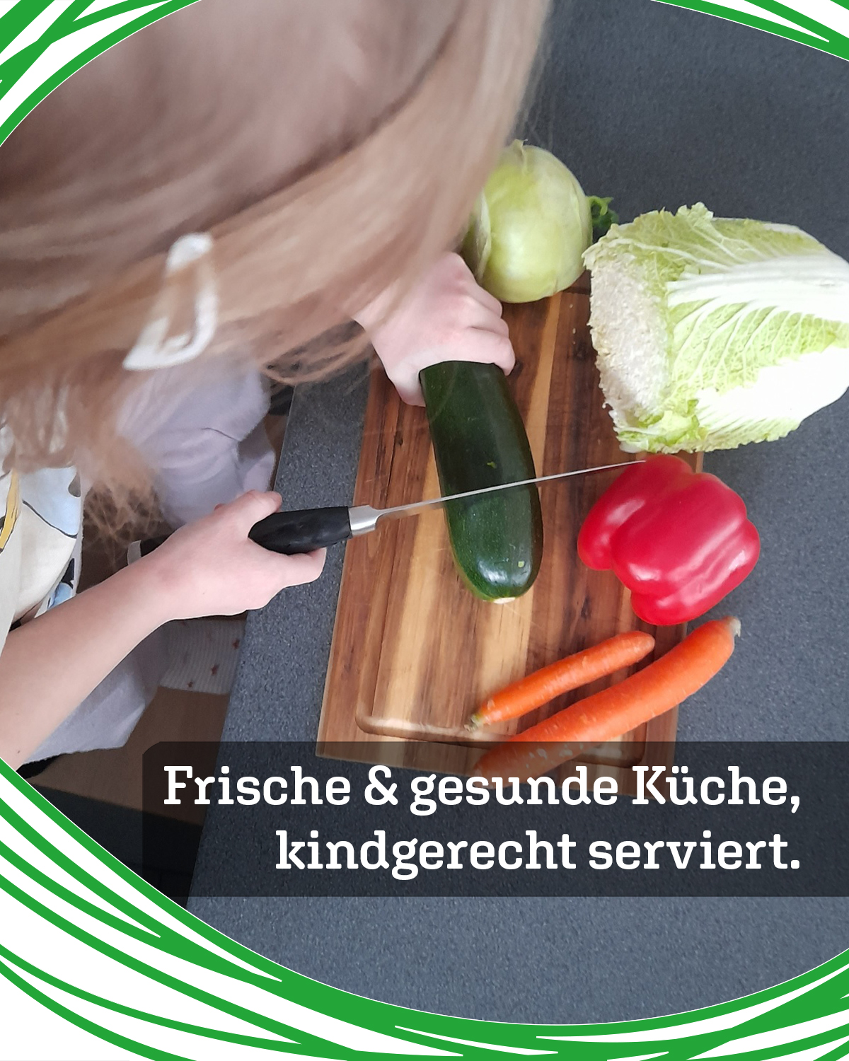 Child cutting a zucchini on a wooden board with a knife, surrounded by cabbage, a red pepper, and carrots.
