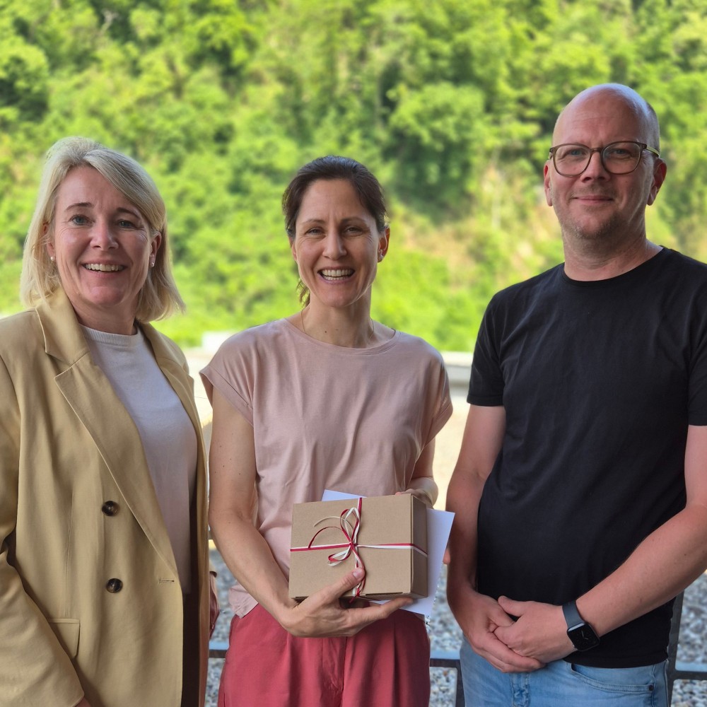 Betriebsärztin Veronika Tschann (Mitte) und unsere Geschäftsführung (Yvonne Antretter-Wiedl, li, und Patrick Malang, re) lächeln in die Kamera. (c) KibeV