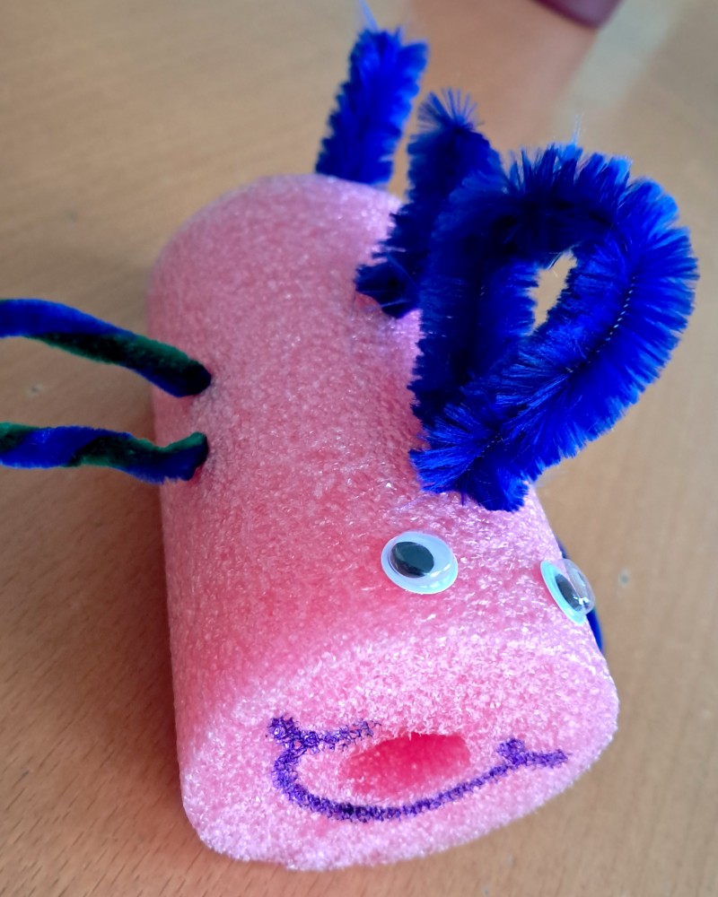 Selbstgebastelter Regenbogenfisch aus einer rosa Poolnudel und blauen Pfeifenputzern. (c) KibeV