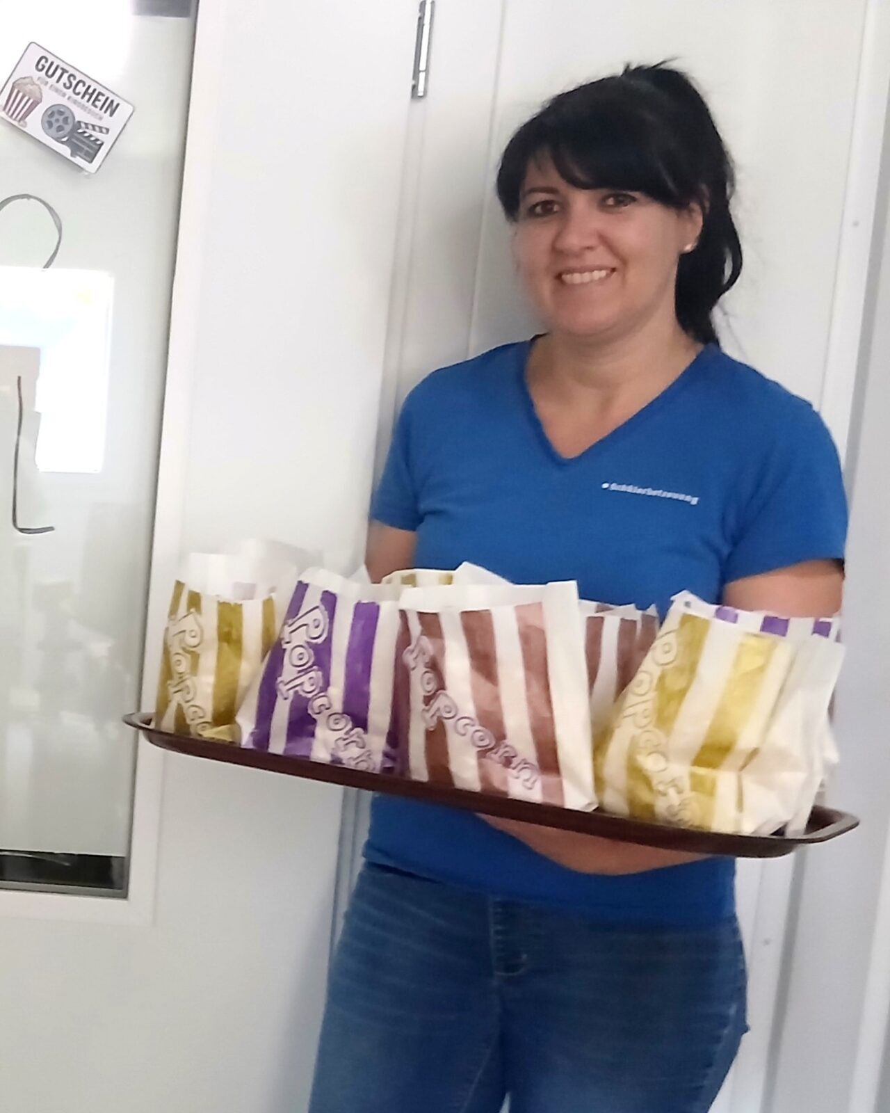Zwei Betreuerinnen der Ferienbetreuung Schwarzach stehen mit Popcorn und Eintrittskarten vor dem "Kinosaal" in ihrer Einrichtung. (c) KibeV