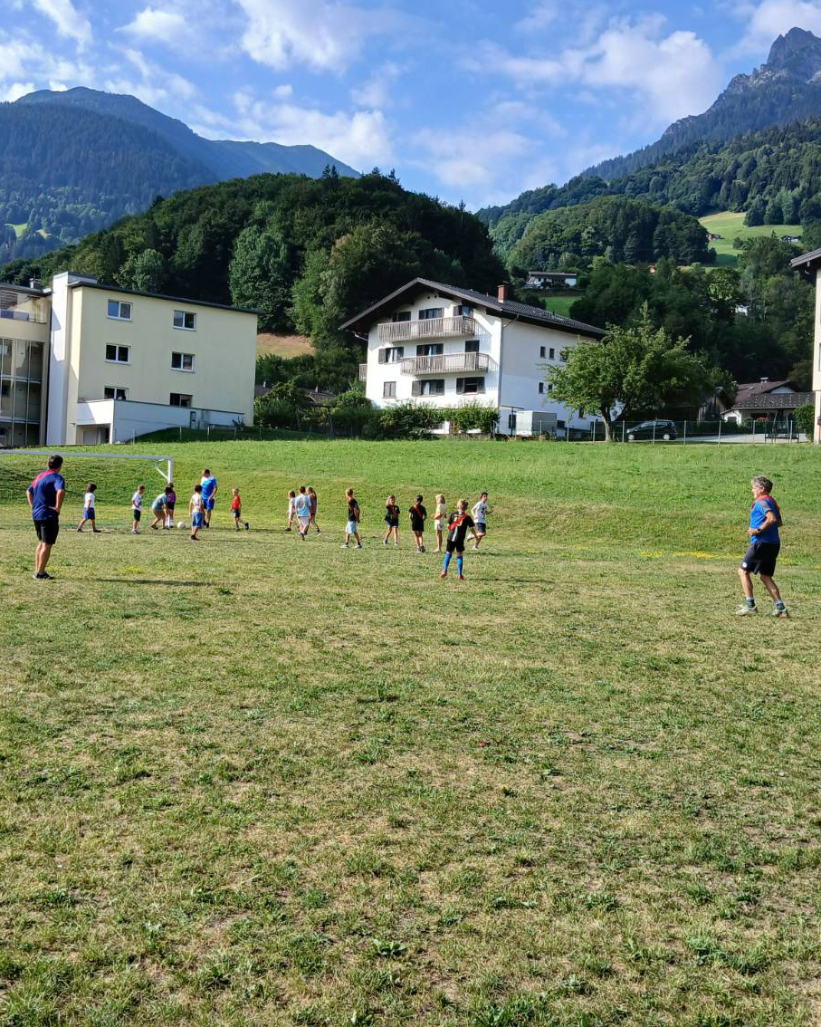 Kinder spielen mit allen drei Bürgermeistern auf einem Fußballplatz Fußball. (c) KibeV
