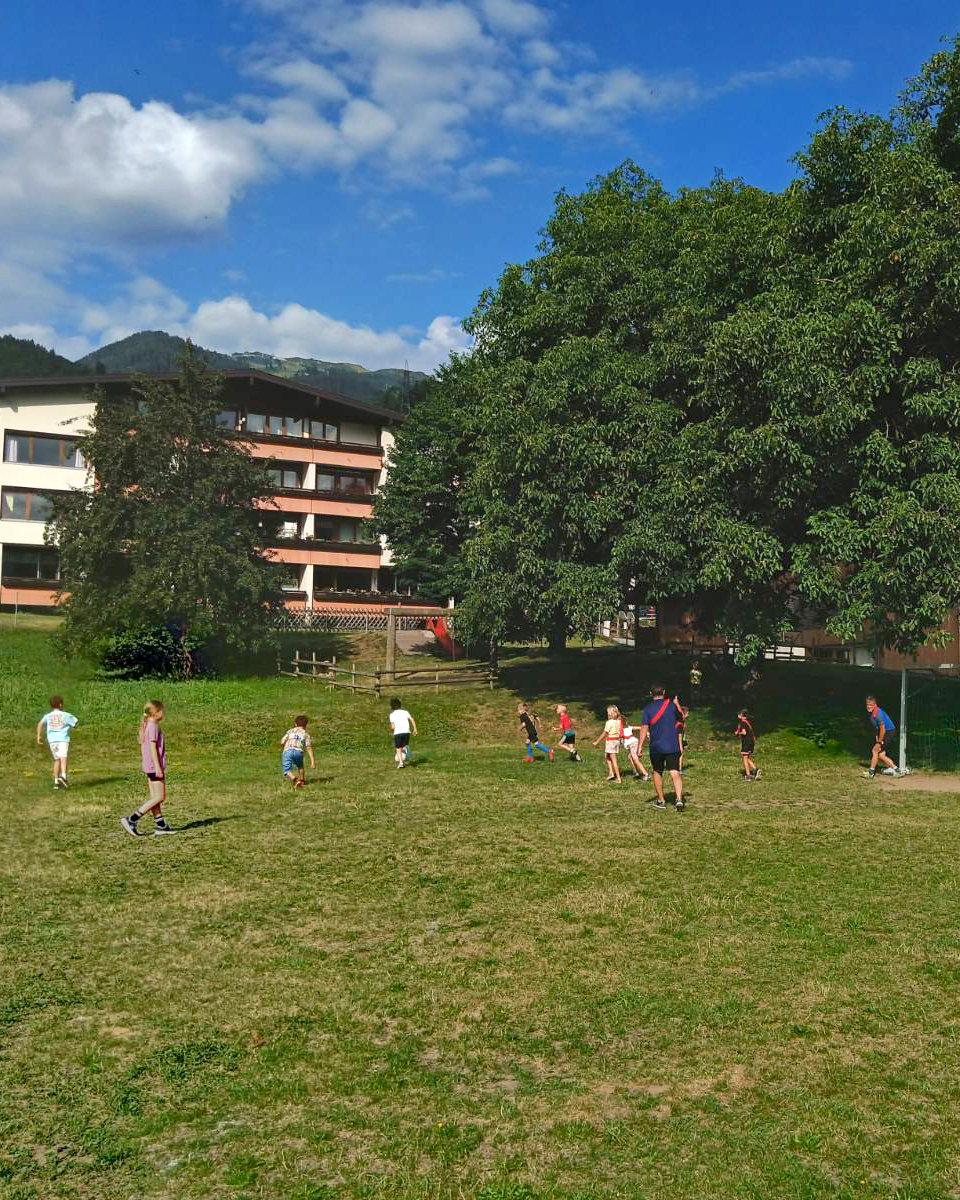 Kinder spielen mit Bürgermeistern auf einem Fußballplatz Fußball. (c) KibeV