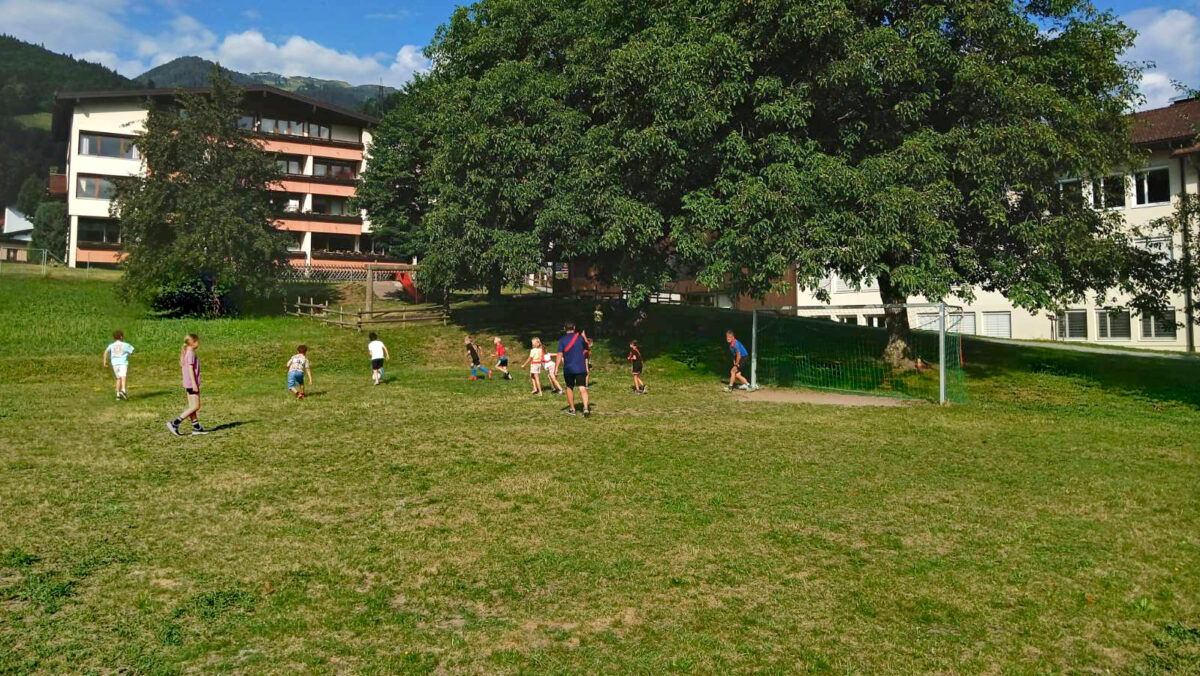 Kinder spielen mit Bürgermeistern auf einem Fußballplatz Fußball. (c) KibeV
