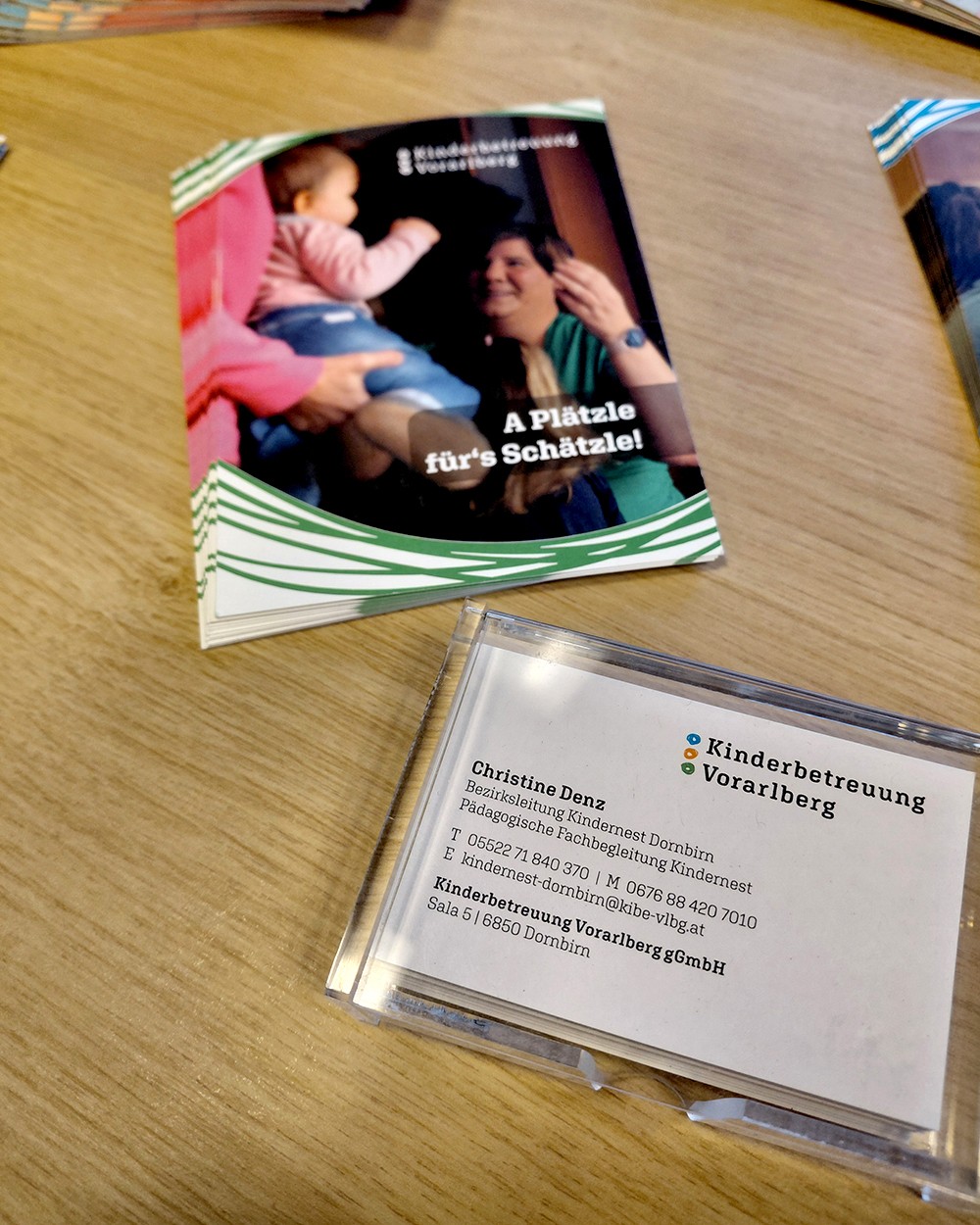 Etui mit Visitenkarten von Christine Denz liegen auf einem Tisch neben Flyern zu freien Plätzen in den Kindernestern. (c) KibeV