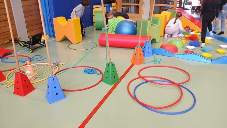 Kinder spielen im Turnsaal an verschiedenen Bewegungsstationen. (c) KibeV