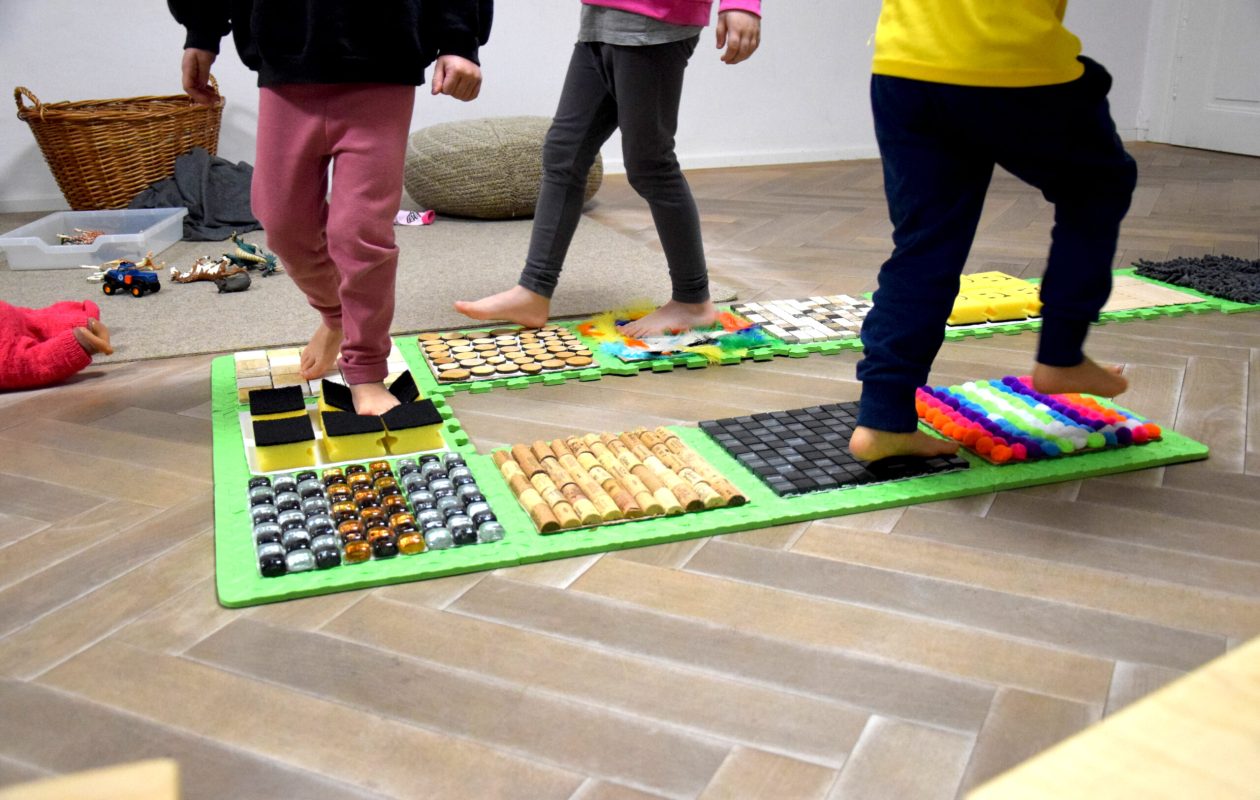 Kinderfüße gehen über einen Indoor-Barfuß-Weg im Zwergengarten Steinebach. (c) KibeV